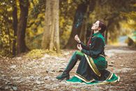 Woman in Green and Black Dress Holding a Stick