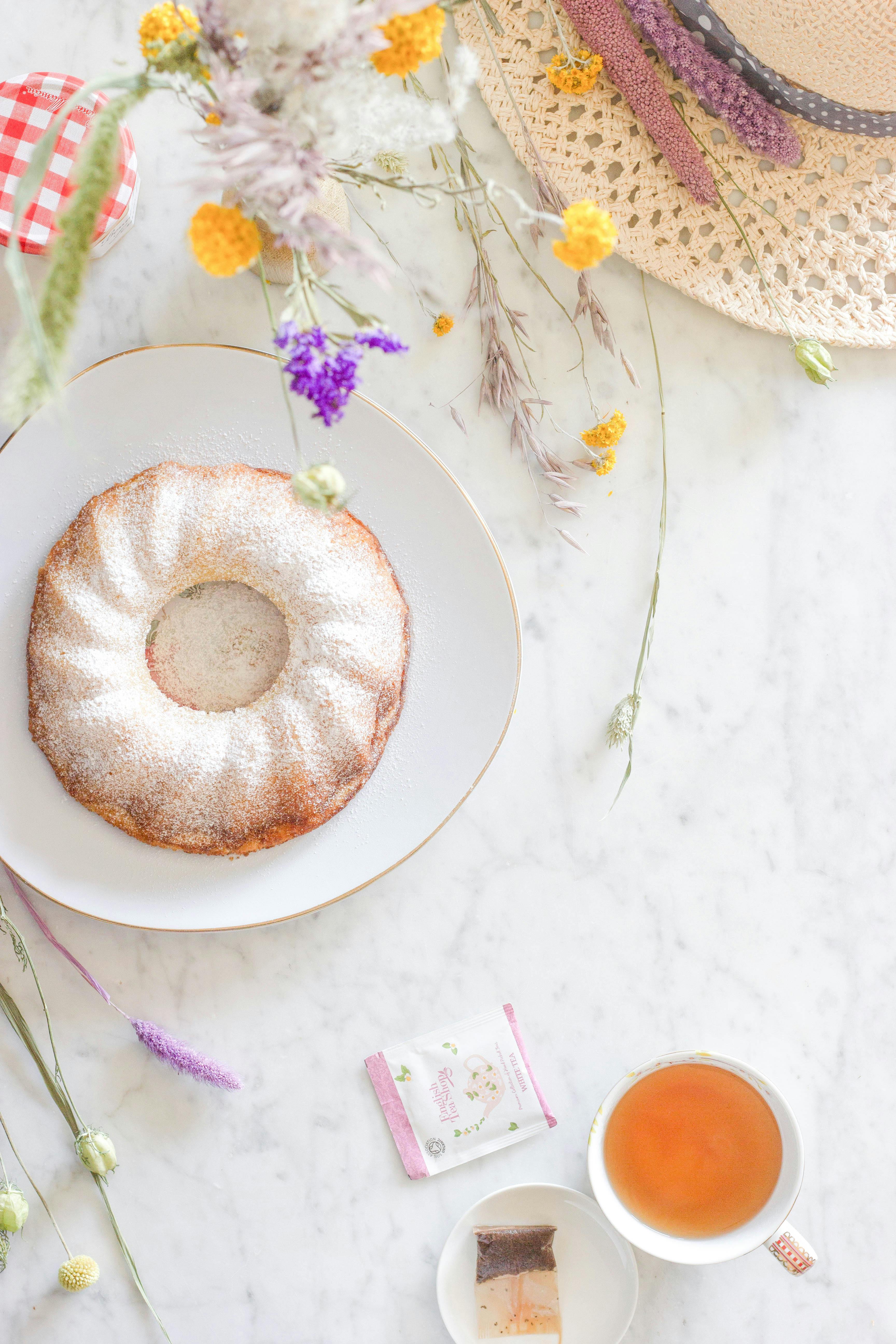 Aerial shot of a doughnut and tea beautifully arranged on a marble table.