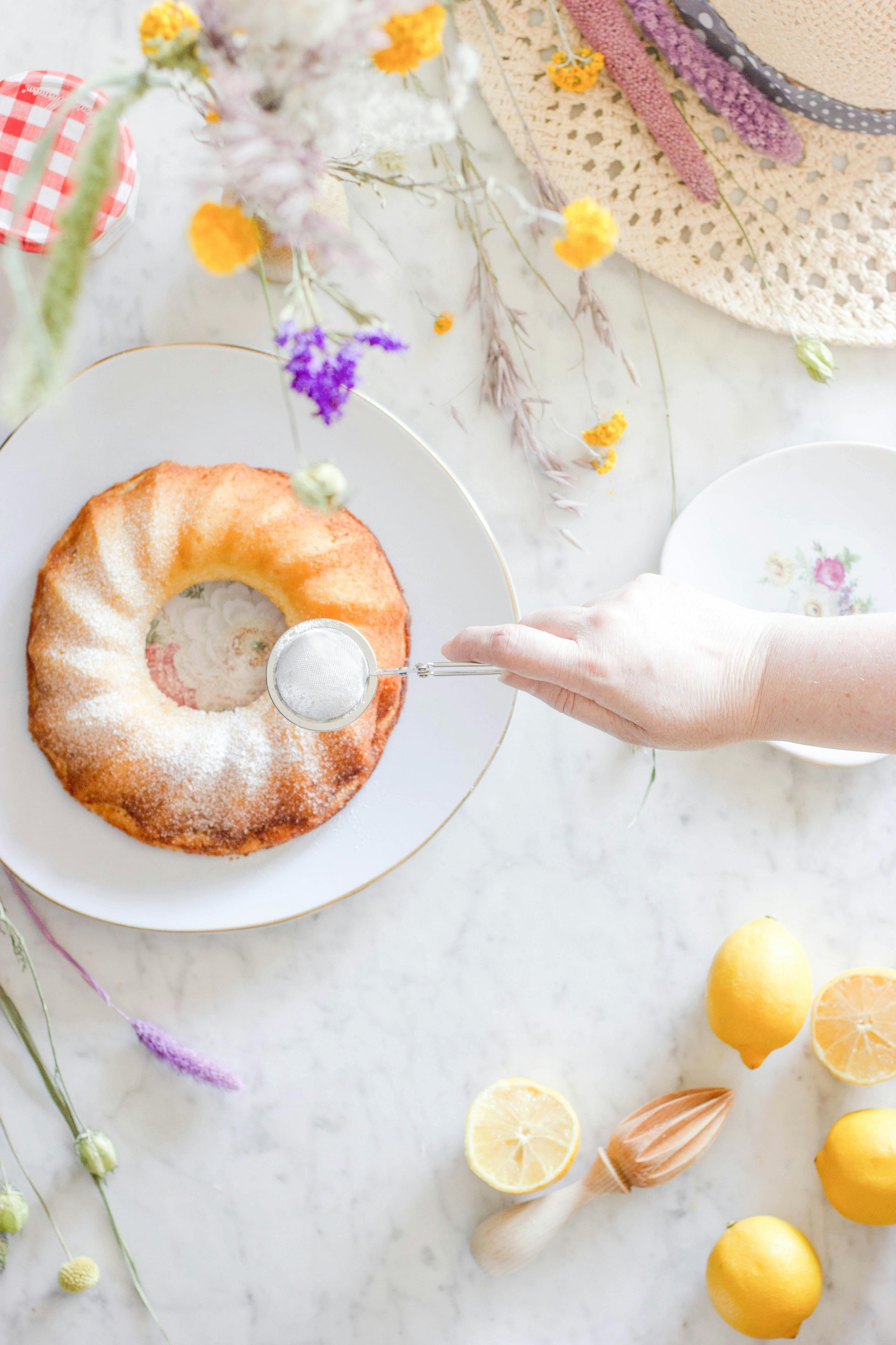 Top-down view of a lemon bundt cake dusted with sugar, alongside fresh lemons.