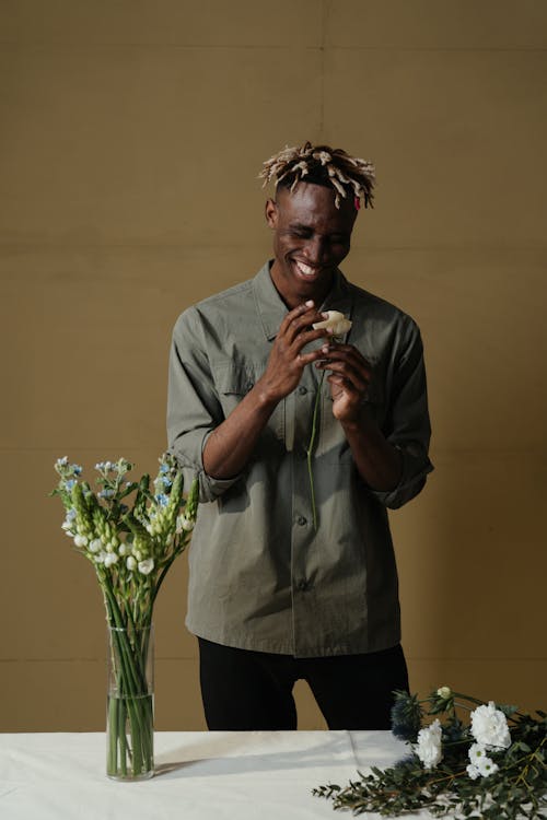 Man in Gray Button Up Shirt Holding Green Plant