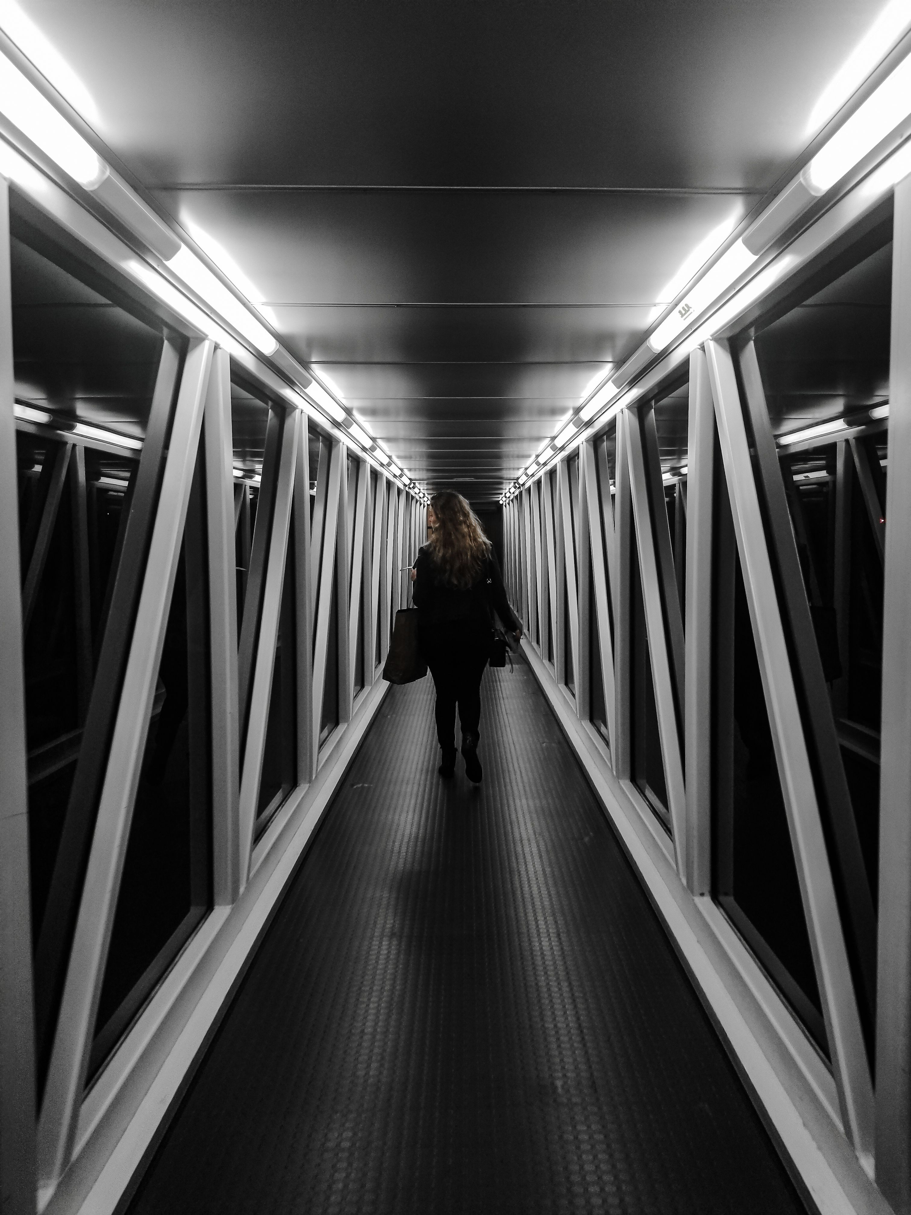 Woman in Black Jacket Walking on Hallway · Free Stock Photo