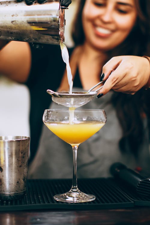 Woman Pouring Yellow Liquid From Drink Mixer