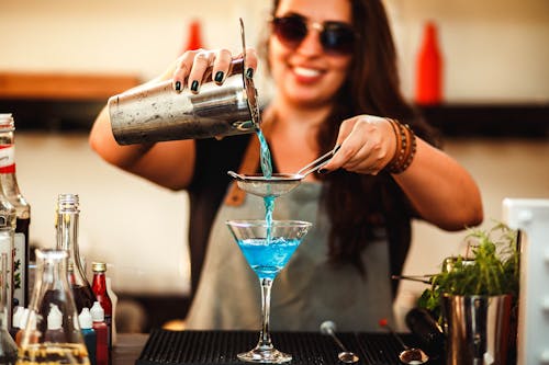 Free Crop cheerful woman preparing homemade blue cocktail in bar Stock Photo
