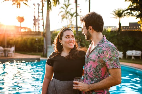 Photo of Couple Smiling While Standing on Poolside