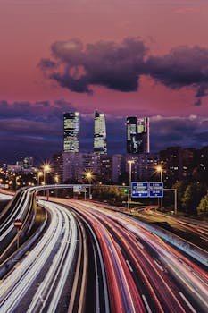 A breathtaking view of Madrid's skyline at dusk, showcasing dynamic light trails on the highway.