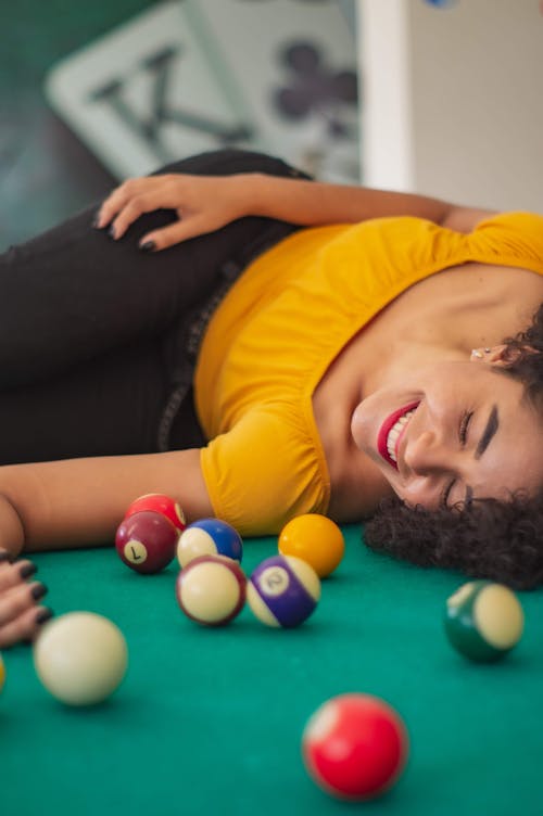 Woman in Yellow Shirt Lying on Billiard Table