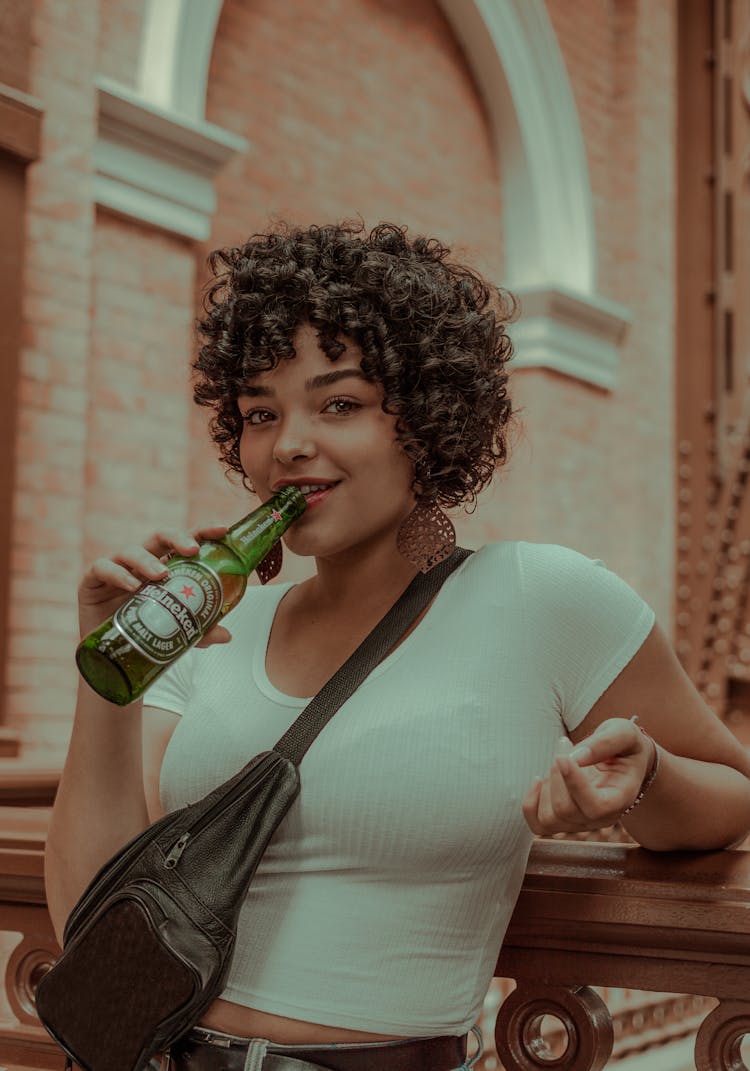 Content Black Woman Drinking Beer From Bottle Near Old Building