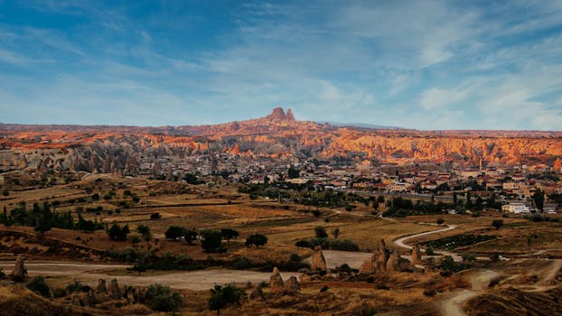 Breathtaking view of Cappadocia with unique rock formations and town at sunset.