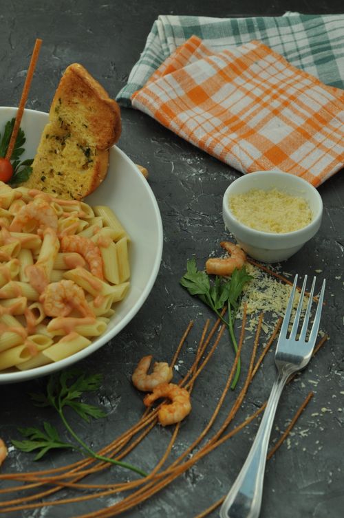 Free Close-up of shrimp pasta, garlic bread, and parmesan in a cozy setting. Stock Photo