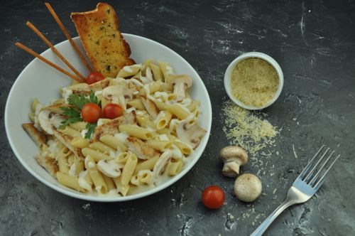Free Appetizing Italian pasta dish with garlic bread, mushrooms, and cherry tomatoes on a gray surface. Stock Photo