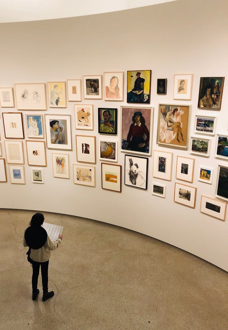 Unrecognizable Woman Near Wall With Collection Of Pictures In Gallery