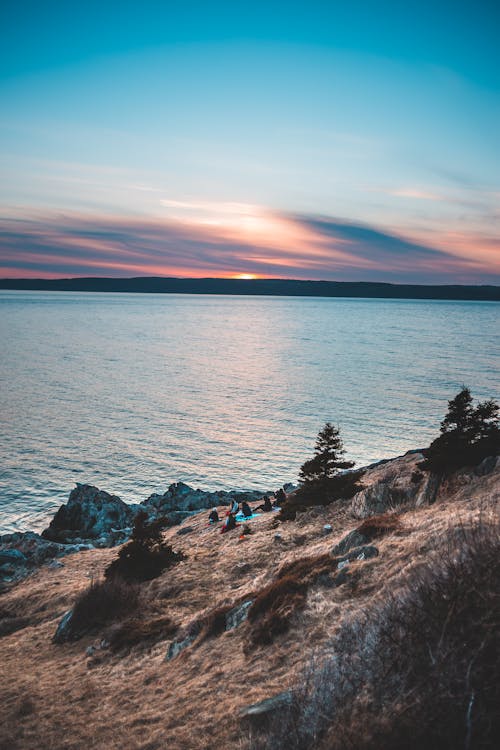 Mountain near sea under cloudy sky at sunset