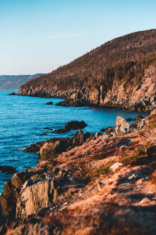 Rough mountains near bright blue ocean under serene sky