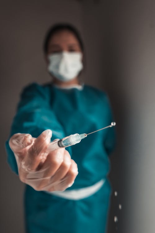 Free Unrecognizable doctor showing syringe with pouring medicine drops Stock Photo