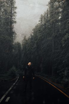在加拿大阿尔伯塔省的一条雨林道路上，站着一个穿着雨衣的男人