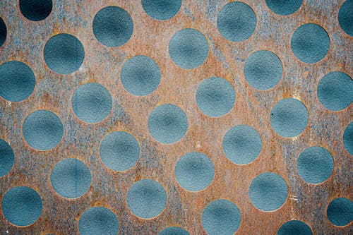 Backdrop of rusty metal with circle pattern near concrete wall
