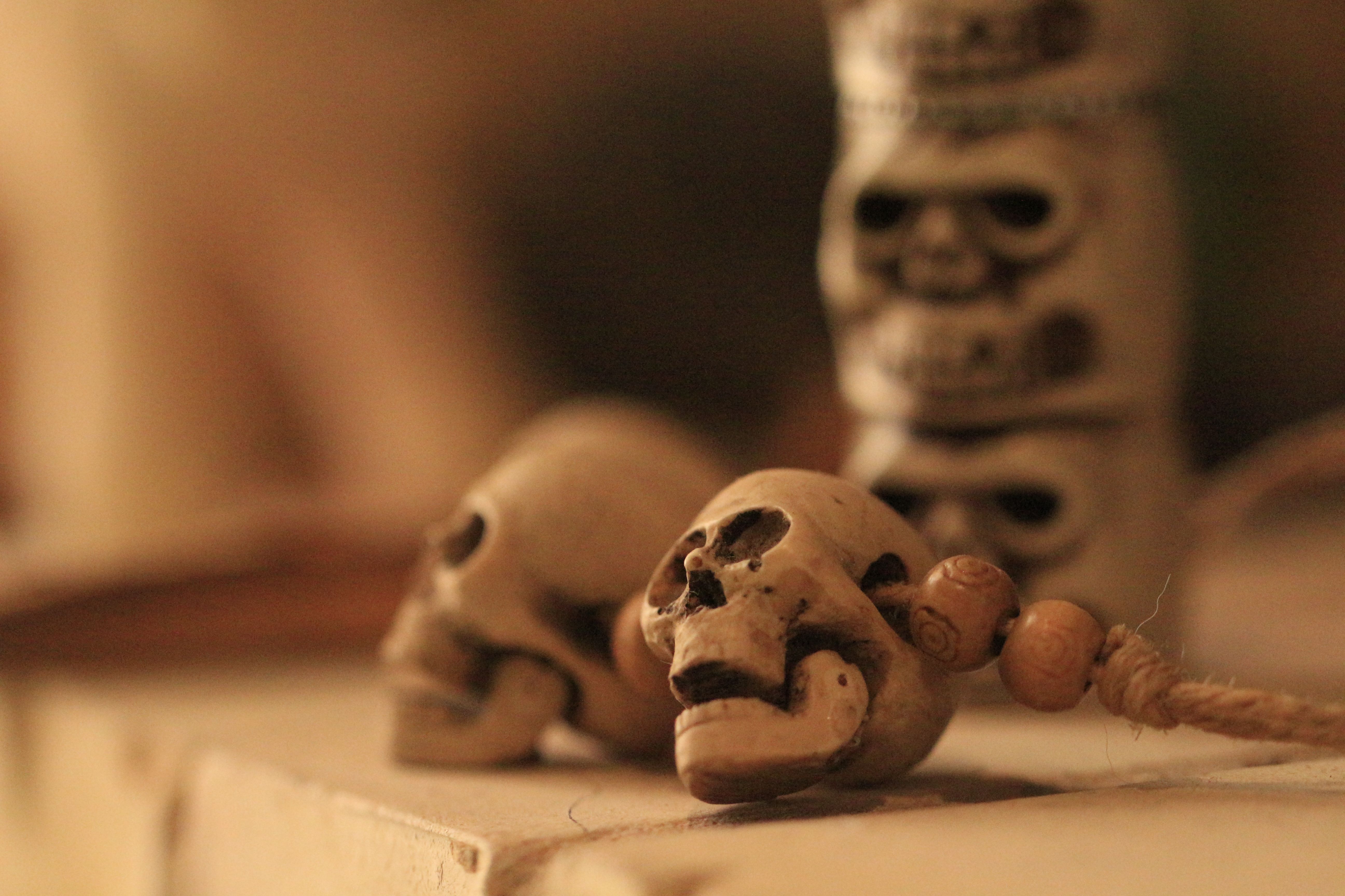 Intricate wooden skulls with beads used for ritualistic decoration, set in warm light.
