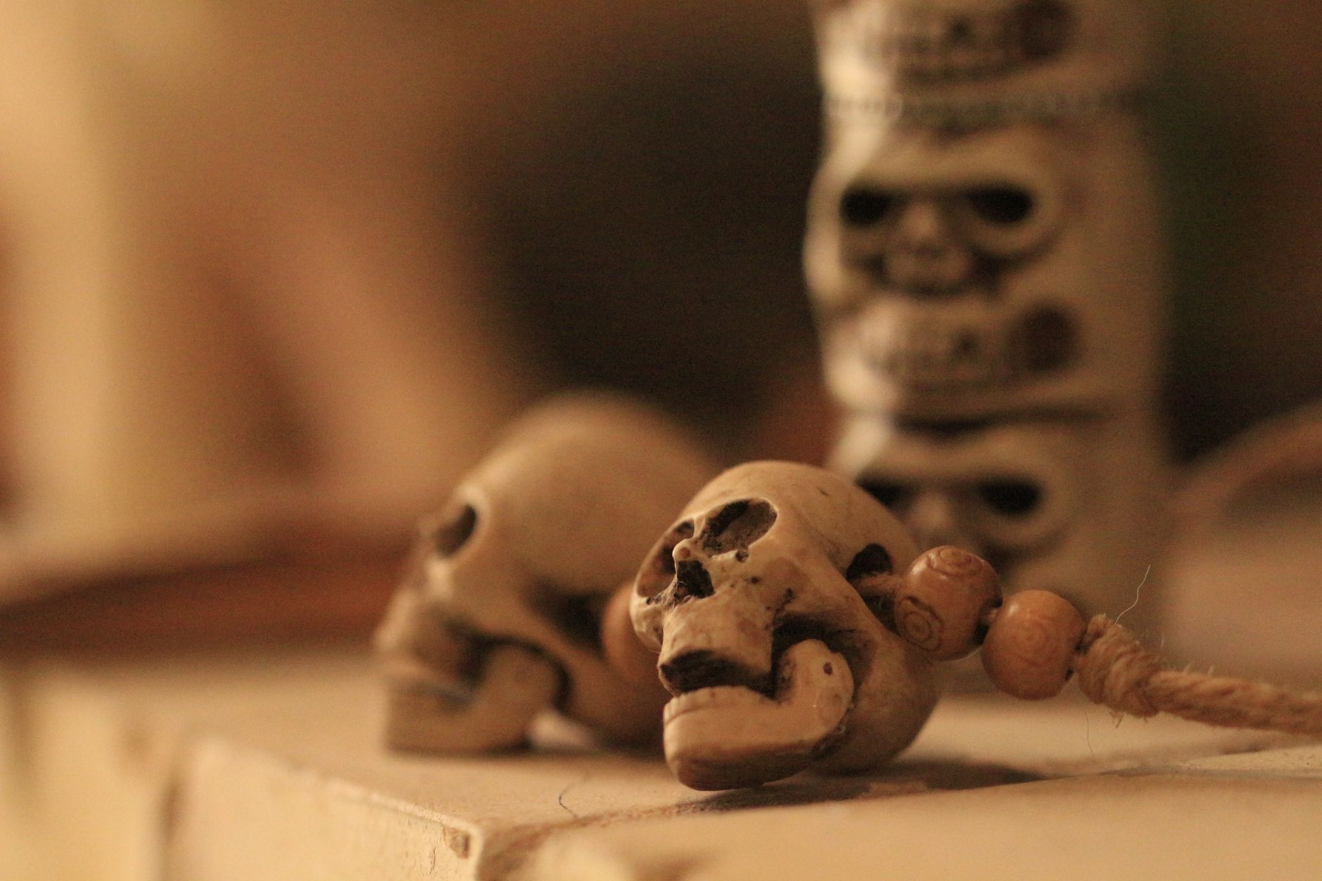 Intricate wooden skulls with beads used for ritualistic decoration, set in warm light.