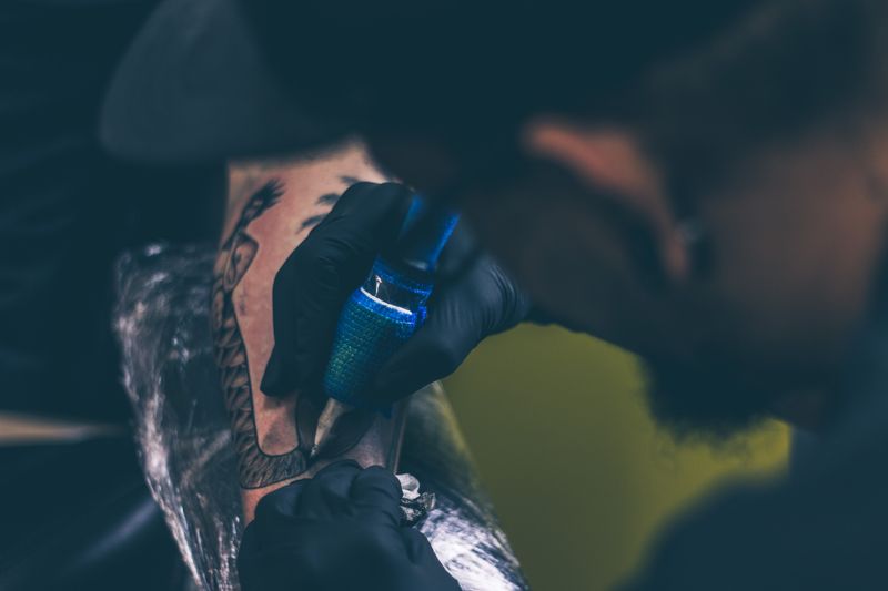Tattoo artist working on a client's arm with a tattoo machine