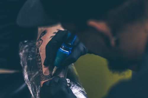 Free Close-up of a tattoo artist creating art on a client's arm. Stock Photo