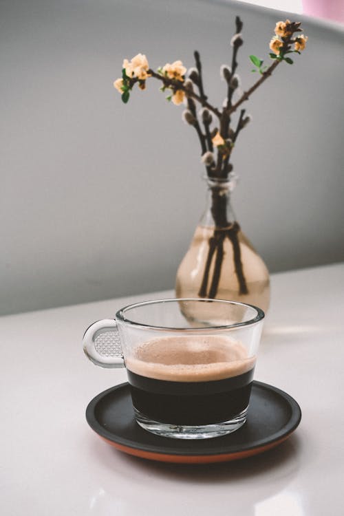 Vase with blossoming willow stem composed with coffee cup