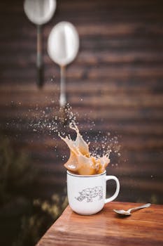 Coffee splashes energetically in a white mug, set against a wooden backdrop.