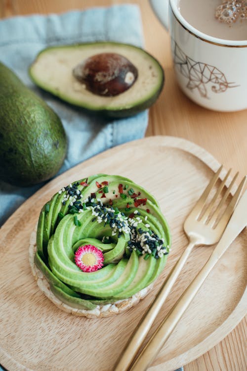 Free Green and Brown Pastry on Brown Wooden Round Plate Beside Silver Fork Stock Photo