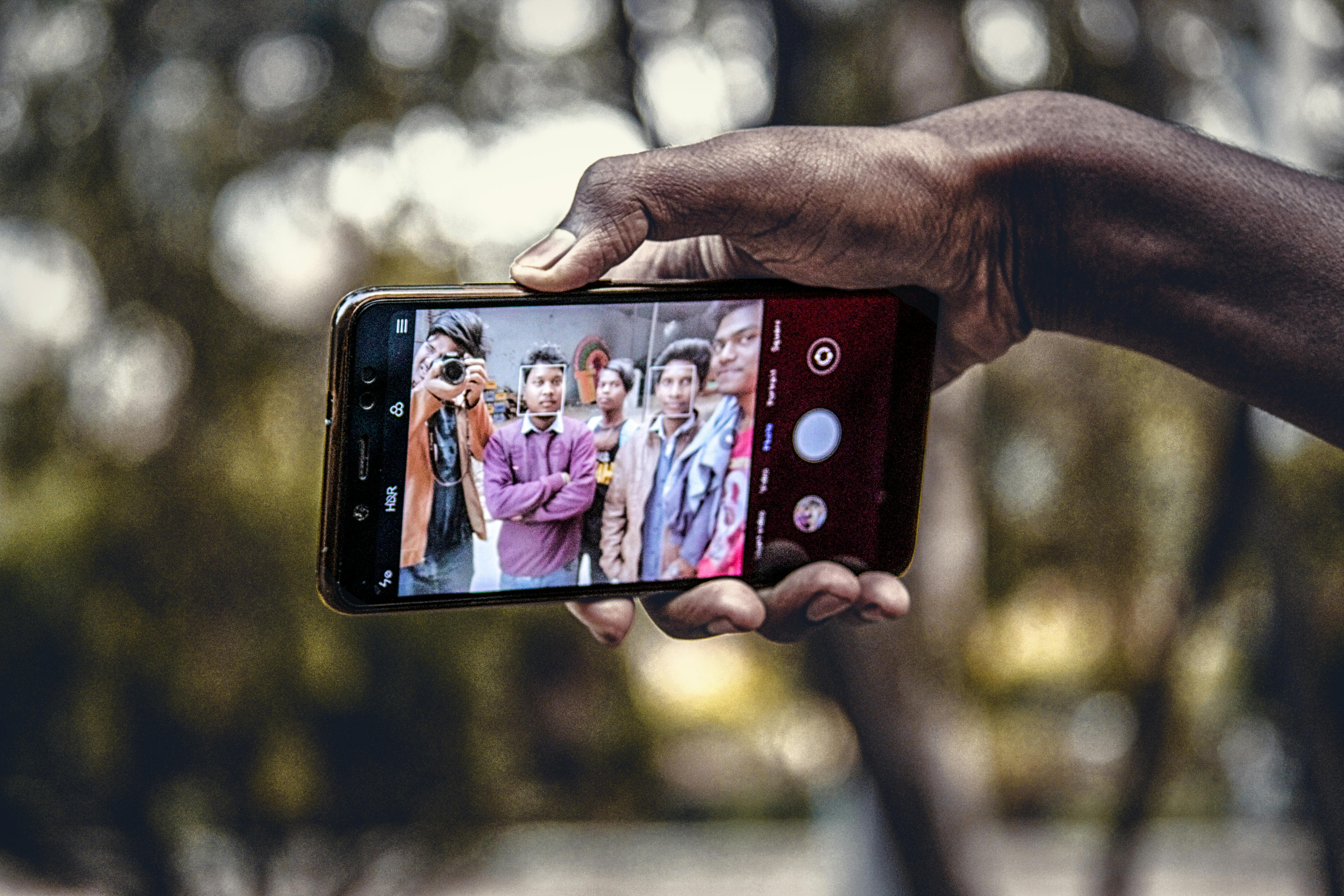 close up shot of a person holding a mobile phone while taking picture