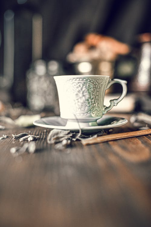 Free Old fashioned carved porcelain cup of coffee with saucer served on wooden table during breakfast Stock Photo