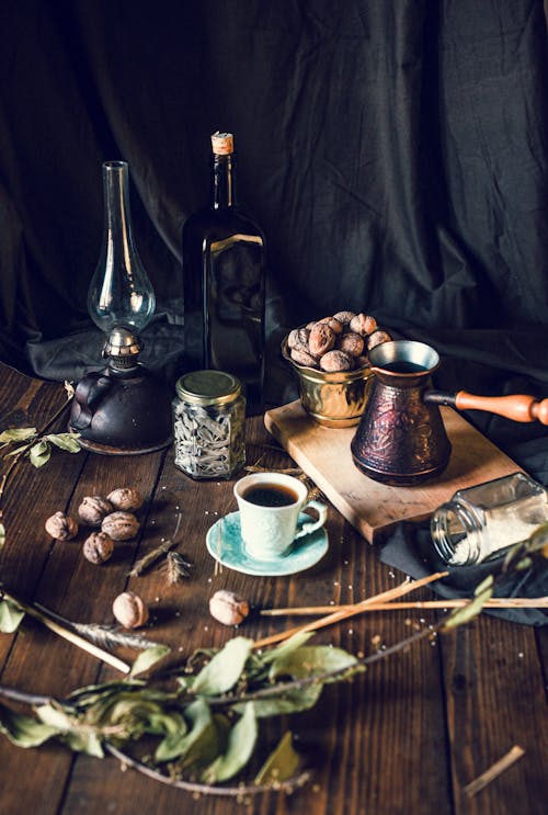 咖啡杯和壶与核桃碗放在桌上用各种香料和复古装饰品