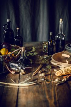 From above of bottles with assorted oil and vinegar placed on wooden table in kitchen near fruit basket composed with corn and herbs