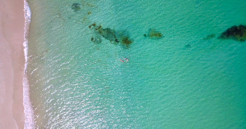 Atemberaubende Luftaufnahme von klarem türkisfarbenem Wasser und einem Sandstrand in Neuseeland.