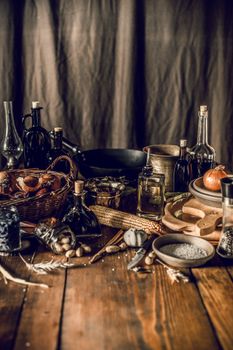 Kitchen equipment and bottles of sauces and condiments composing with groceries on wooden table in kitchen