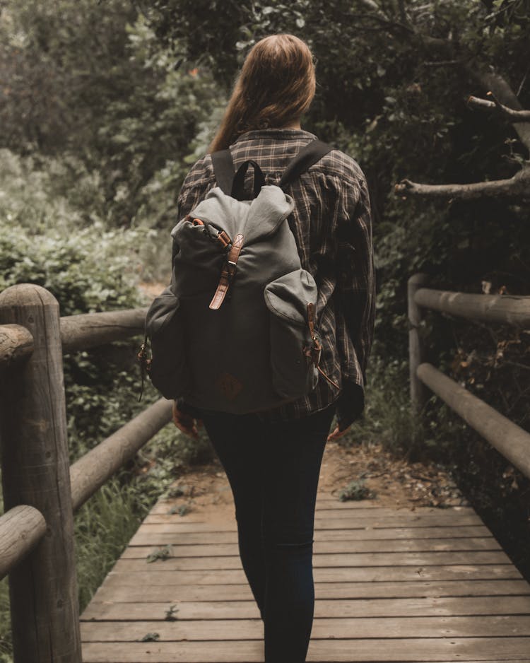 Woman Walking On Bridge Carrying Backpac