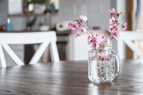 Vase with blossoming cherry tree branches on table