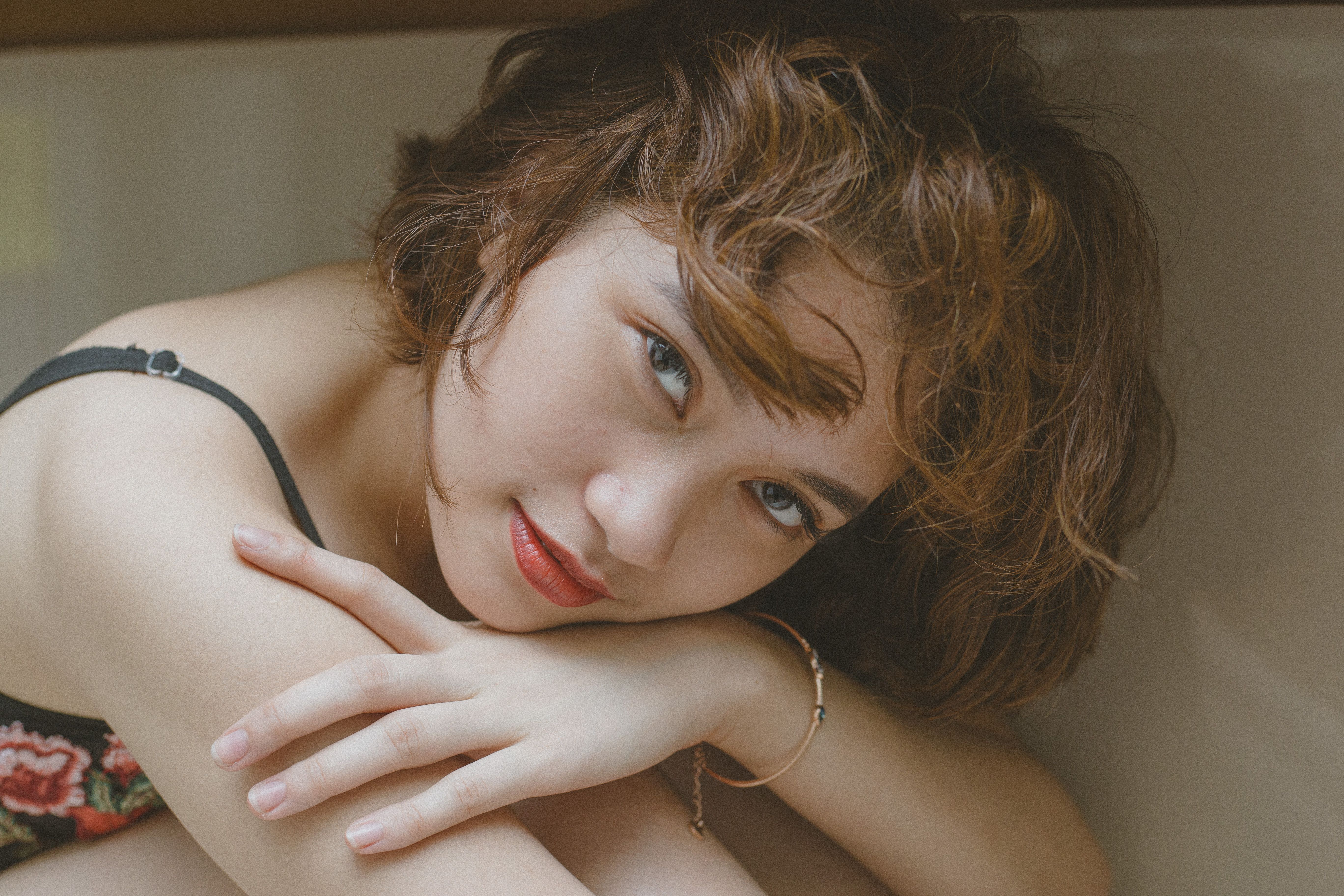 A close-up portrait of a young woman with short hair and red lipstick, posing indoors.