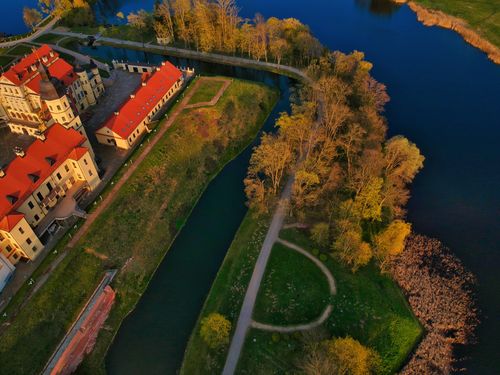 Free Aerial view of majestic historic Nesvizh Castle in Baroque style surrounded by peaceful river and lush greenery in Belarus Stock Photo