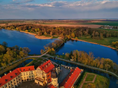 Free Drone view majestic Nesvizh Castle facade forming domed basilica in Baroque style located on lush riverside in Belarus Stock Photo