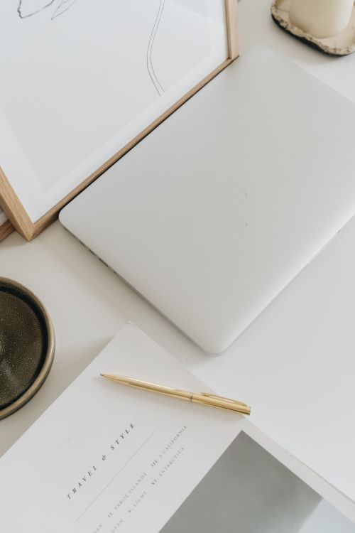 Free Elegant minimalist workspace featuring a closed laptop, art frame, and stylish accessories. Stock Photo