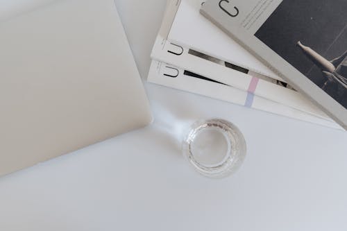 A Magazines and Laptop on the Table Near the Drinking Glass