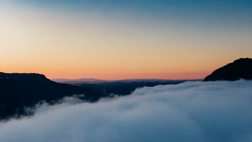 White clouds above silhouettes of mountains at sunset