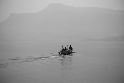 Free Grayscale Photo of People Riding on Boat on Sea Stock Photo