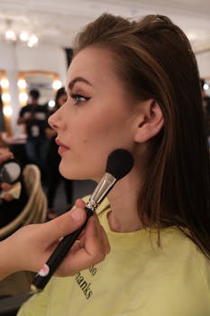 Makeup artist delicately applies blush on a model in a modern salon setting.