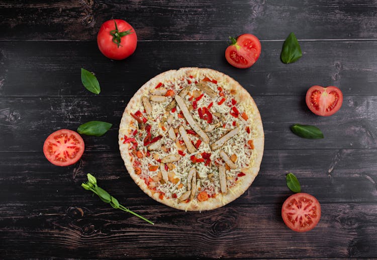 Yummy Pizza Near Cut Tomatoes And Basil Leaves