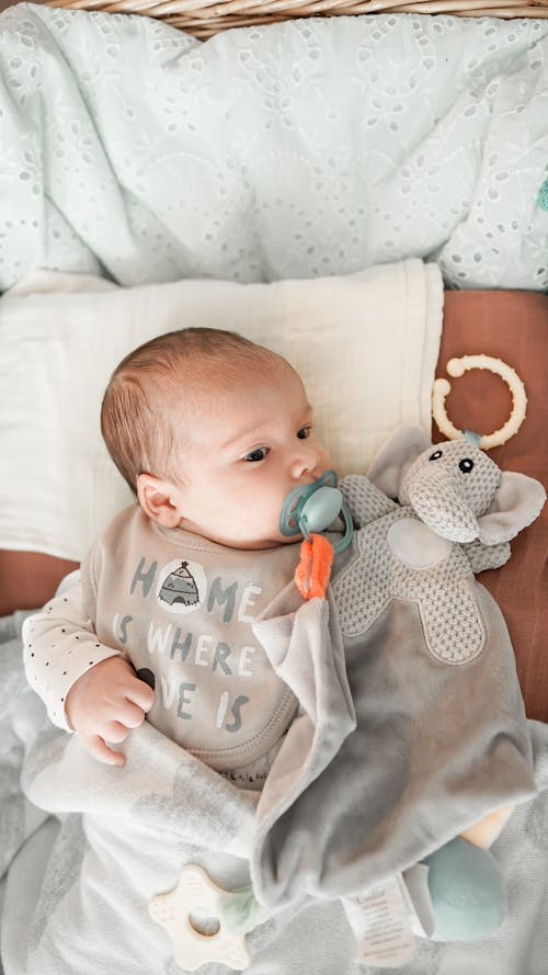 Free From above of cute baby with dummy looking away while lying in cot at home Stock Photo