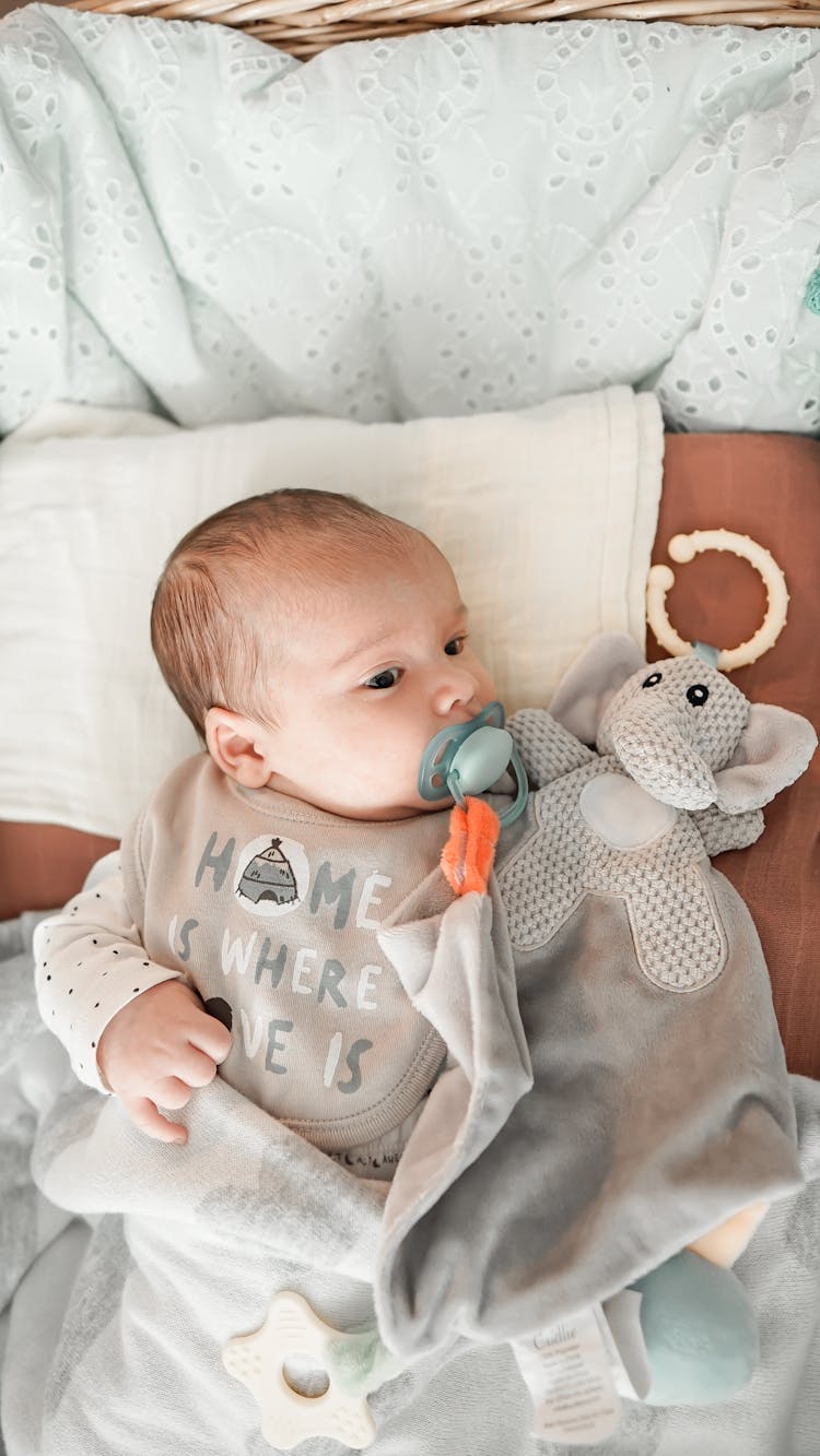 Newborn Baby With Pacifier Resting In Crib