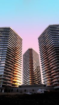 From below of contemporary multistage building exteriors in city under colorful sky at sundown