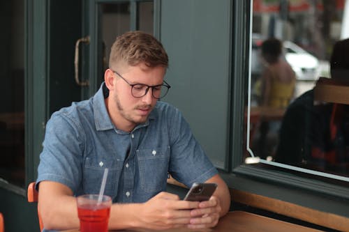 Free Concentrated man chatting on smartphone in street cafe Stock Photo