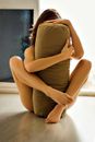 Anonymous barefoot female with legs and arms round yoga bolster sitting on floor