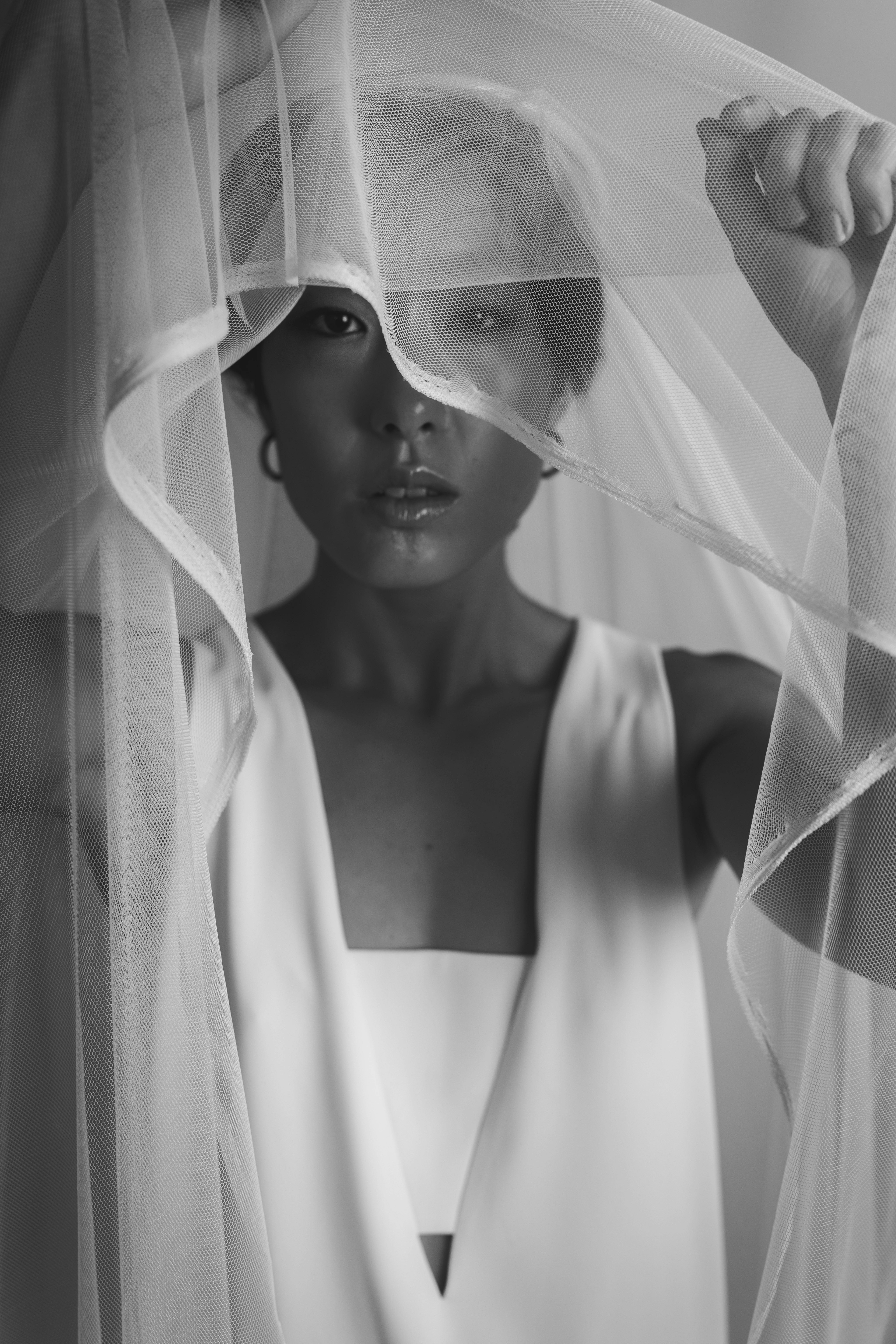 Black and white portrait of an Asian woman in a veil, expressing elegance and mystery.